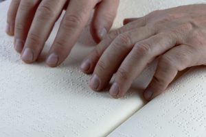 Hands reading a braille document.
