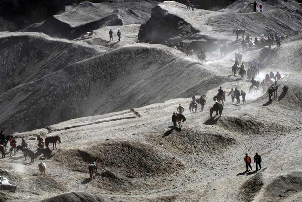 A group of tourists hauling up the steep sandy path on horseback towards the rim of Mt. Bromo to witness an active volcano from close quarters. Photo: Sugato Mukherjee