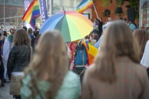 Female LGBTQ-couple in a parade of rainbow umbrellas.