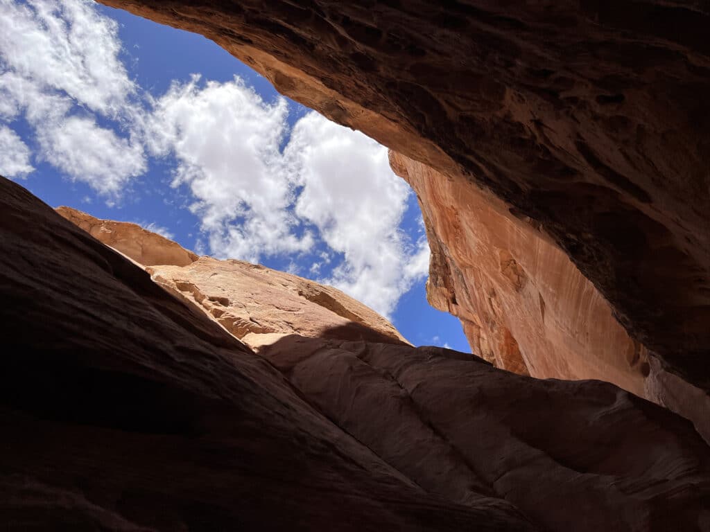 Fluffy white clouds floating through bright blue skies over the slot canyon.  Photo: Thomas Späte
