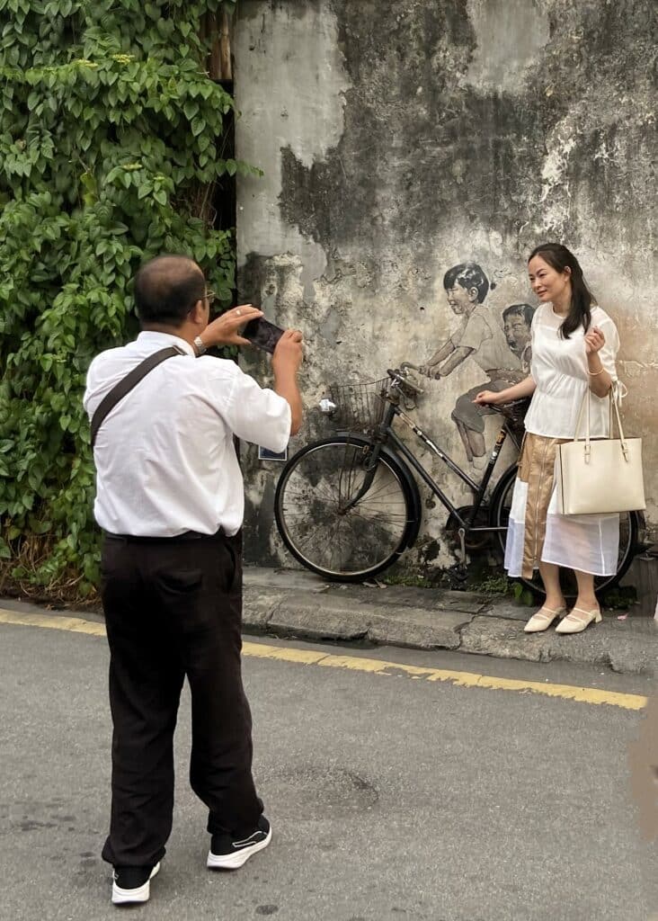 Family taking a photo with street art in Penang.